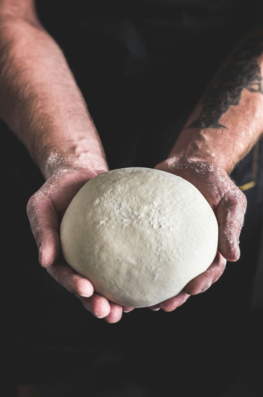 Hände halten frischen Pizzateig